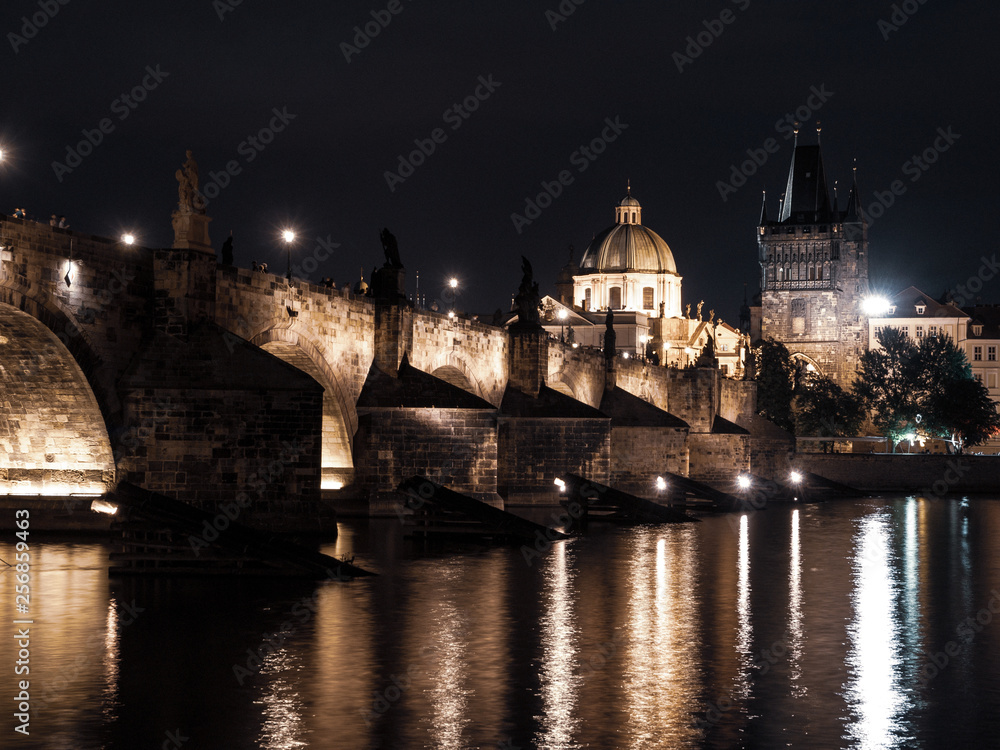 Illuminated Charles Bridge reflected in Vltava River by night. Prague, Czech Republic