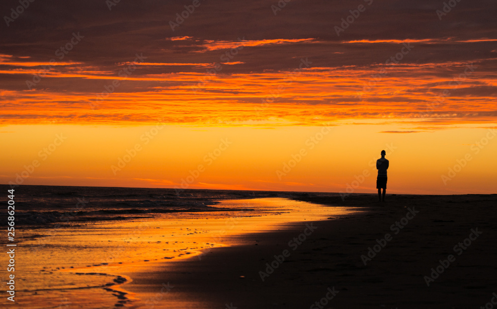 silhouette of man on the beach at sunset