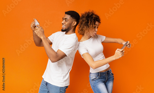 Excited young man and woman playing together on smartphones