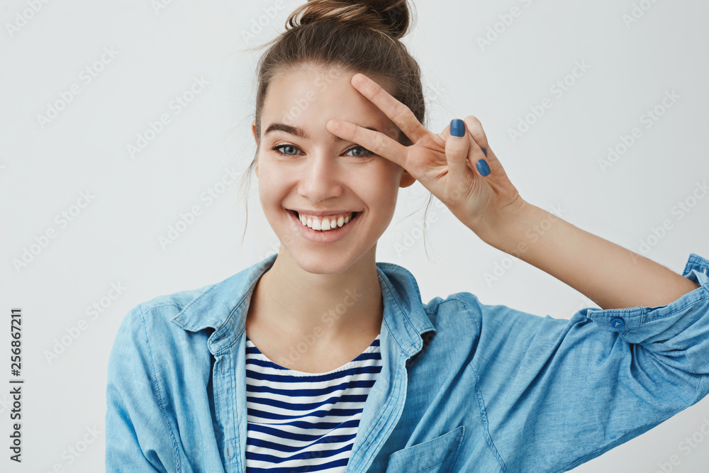 Waist-up studio shot carefree aspiring ecstatic attractive young european woman smiling positively white teeth, showing peace lucky sign pressed hand forehead, feeling happy upbeat Waist-up studio shot carefree aspiring ecstatic attractive young european woman smiling positively white teeth, showing peace lucky sign pressed hand forehead, feeling happy upbeat