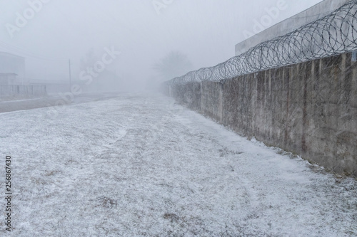 Canvas Print Brick fence with barbed wire on a snowy day
