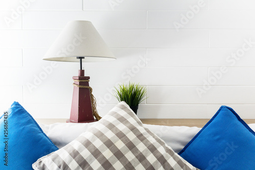 Lamp and green plant on bedside with blue and grey pollows. Hotel room interior background. Text space photo