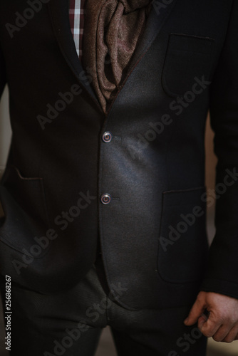 A man with a beard in a black warm coat with a scarf poses to advertise men's clothing in the winter. Advertise men's clothing