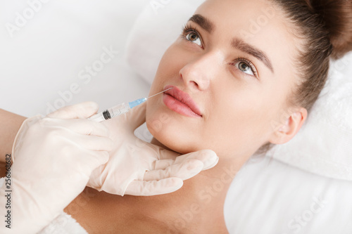 Lip augmentation. Young woman receiving acid injection