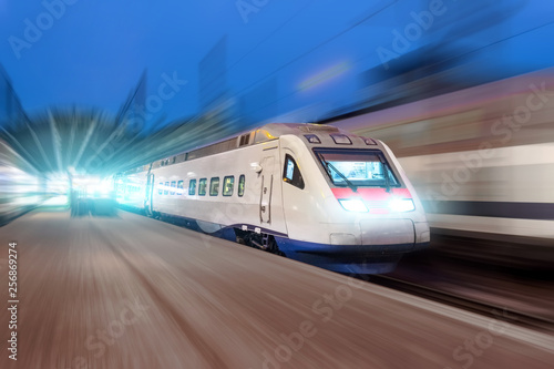 Night railway station, a passing train at speed.