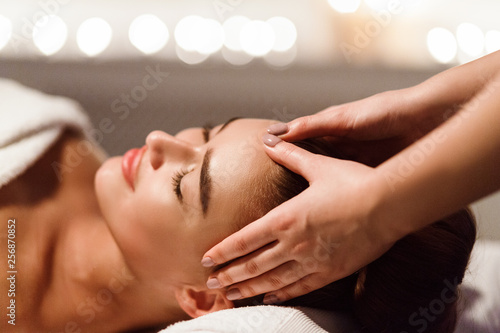 Woman enjoying head massage at spa center