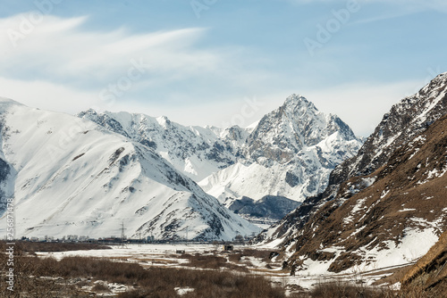 Riverbed in the valley among the snow-capped mountains. Blue sky on the background of snow-capped peaks and riverbed