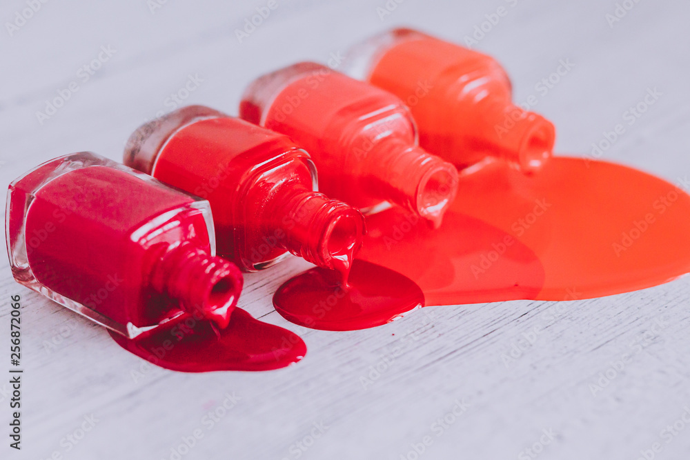 nail polish bottles in different shades of red to orange and purple spilling color on wooden surface nail polish bottles in different shades of red to orange and purple spilling color on wooden surface