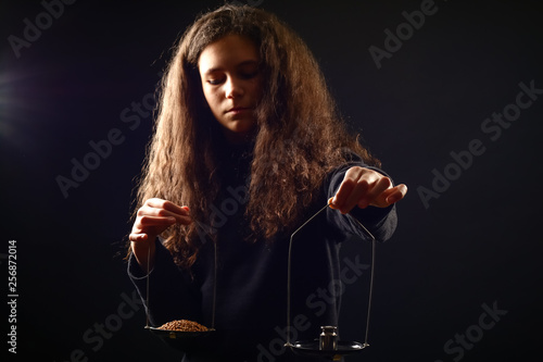Vászonkép Emotional portrait of a girl with long curly hair weighing grain and weights on