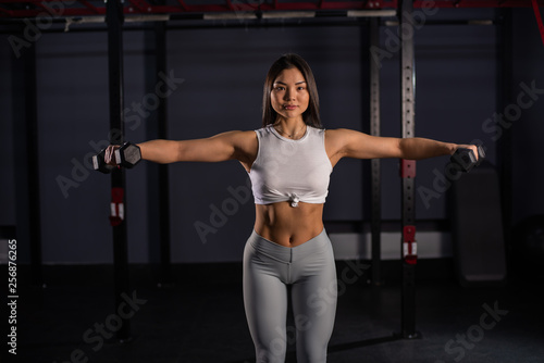 Asian woman lifting dumbbell. Young sporty muscular woman holding dumbbells
