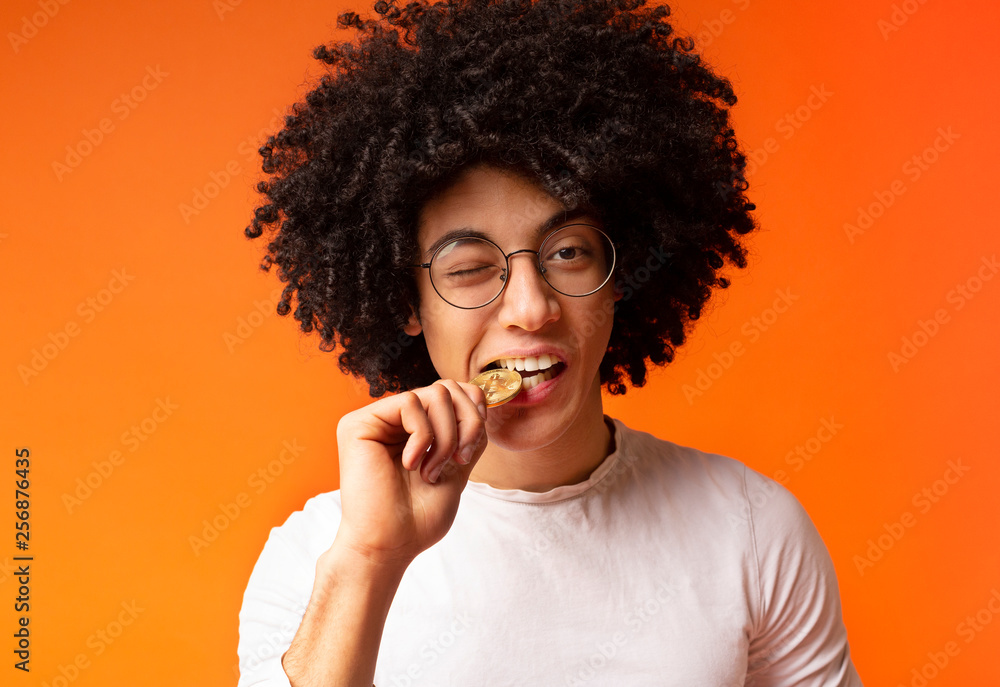 Black man biting golden bitcoin close up Black man biting golden bitcoin close up