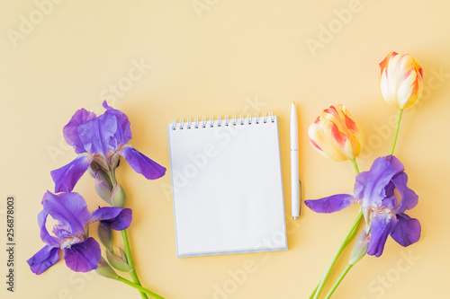 Mockup white notebook with yellow tulips and blue irises on a yellow background