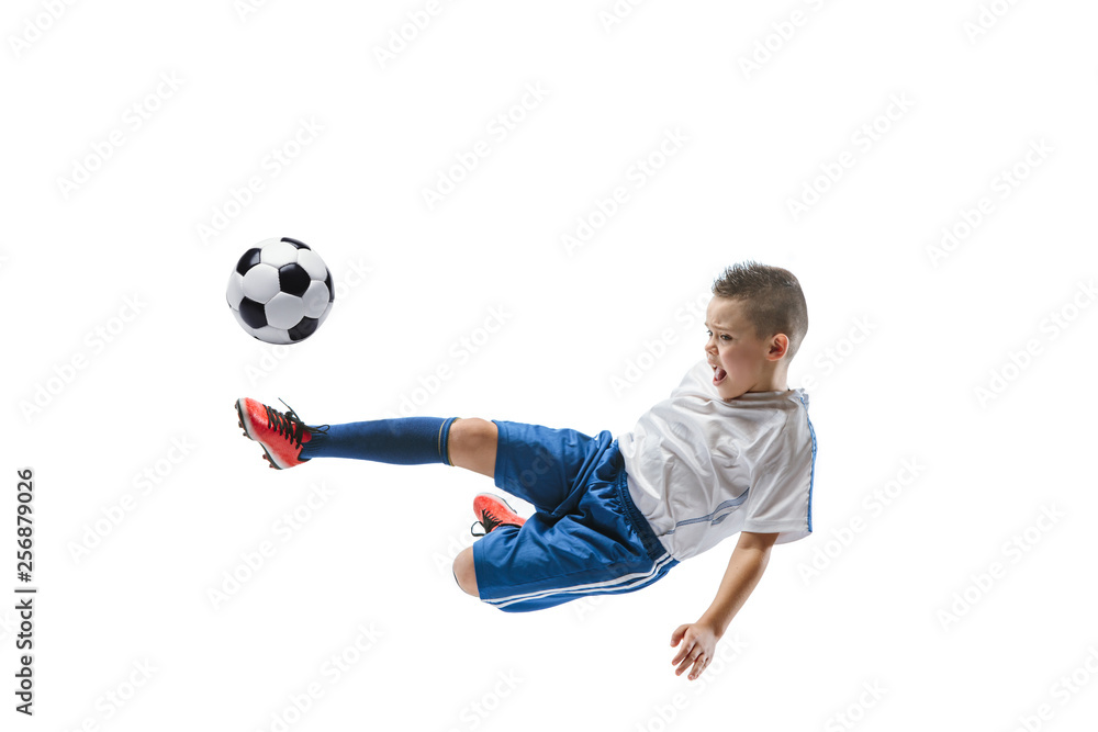 Fototapeta premium Young boy kicks the soccer ball. Isolated photo on white background. Football player in motion at studio. Fit jumping boy in action, jump, movement at game.