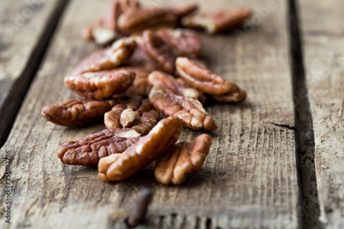 Pecan nuts on a rustic wooden table and pecan nuts in bowl.