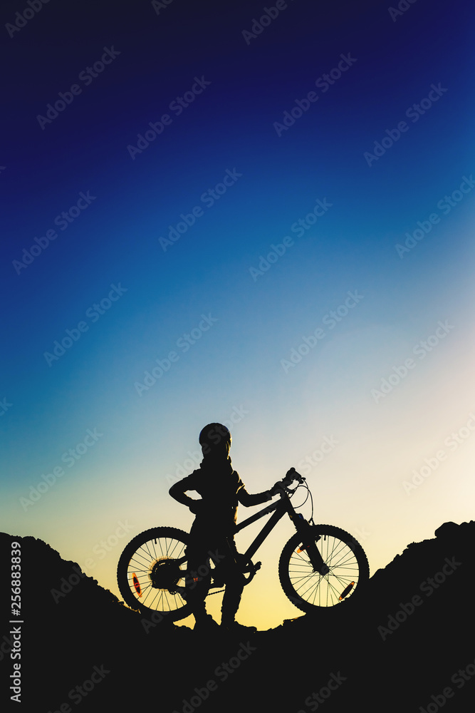 Obraz premium Silhouette of a little girl with a bicycle at sunset