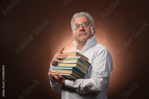Scientific thinker, philosophy, elderly gray-haired man in a white shirt with a books, with studio light