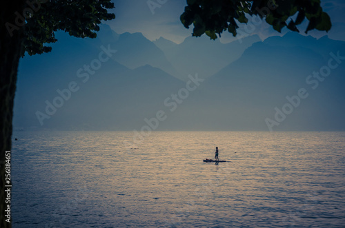 Man on a surfboard with paddle on Lake Leman, Switzerland