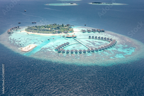 Luxury resort island in Maldives with water bungalow background and blue sea sky aerial view 