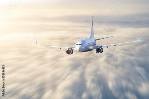 Passenger aircraft in motion blur flies cloudscape evening light before sunset.