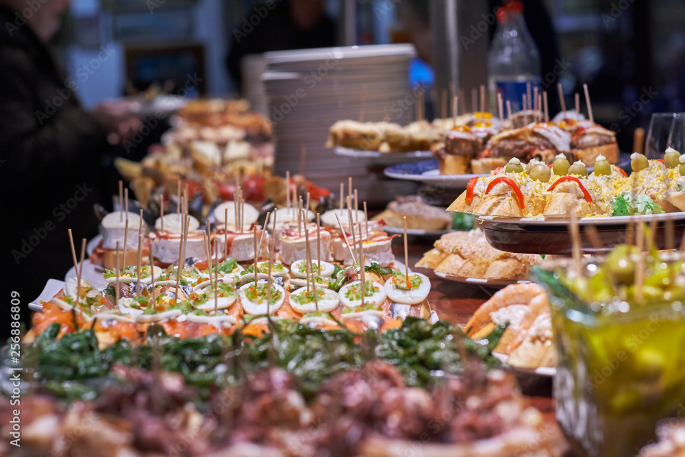 Fototapeta premium Pinchos i tapas typowe dla Kraju Basków w Hiszpanii. Wybór różnych rodzajów żywności do wyboru. San Sebastian
