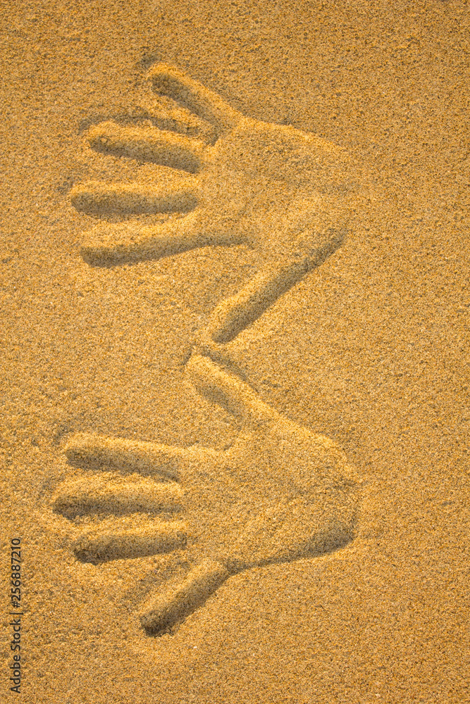 right and left hand imprint in yellow sand close up right and left hand imprint in yellow sand close up