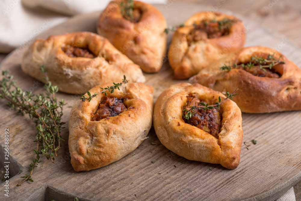 Rasstegai pie with fish filling. Traditional meal of Russian cuisine. Russian dolls in the background