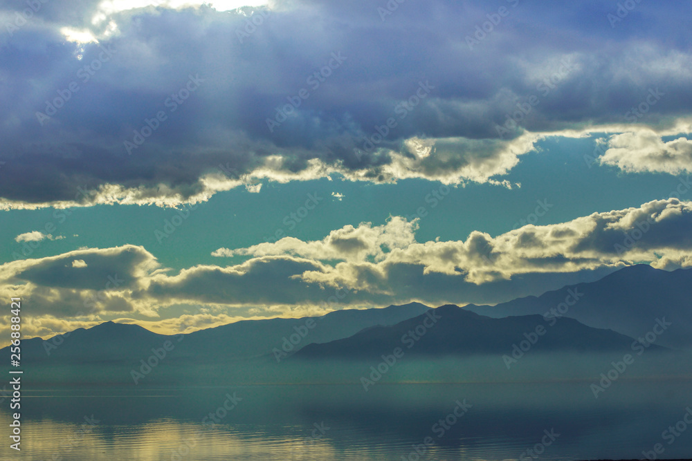 Obraz premium Salton Sea with Calm Water and Sun Breaking Through Clouds