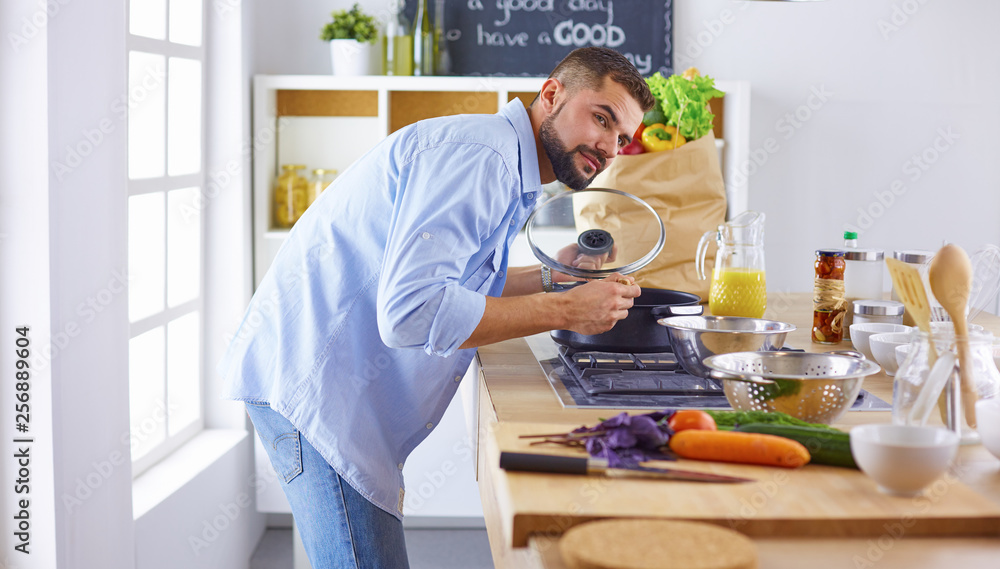 Smiling and confident chef standing in a large kitchen tasting Smiling and confident chef standing in a large kitchen tasting