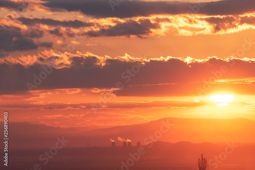 The golden hour of sunset. Orange sky with clouds and yellow sun shining over the mountains. © Inga Av