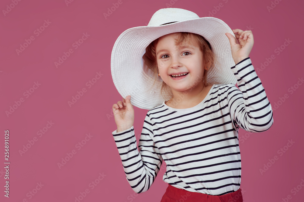 Happy little girl in white hat at pink studio background. Happy little girl in white hat at pink studio background.
