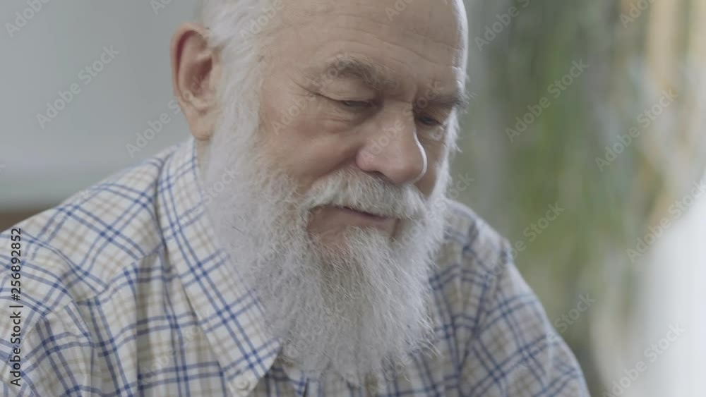 Portrait of thoughtful bearded mature man sitting at home close up. Senior man feels uncomfortable. Old man has a problem Portrait of thoughtful bearded mature man sitting at home close up. Senior man feels uncomfortable. Old man has a problem