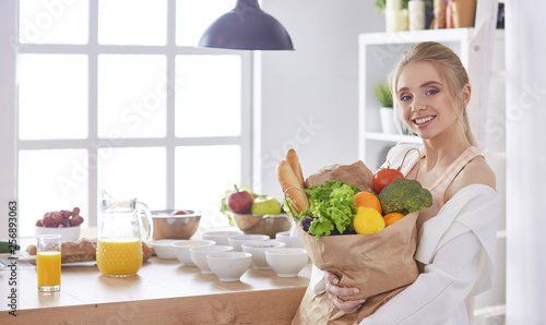 Young woman holding grocery shopping bag with vegetables Standi