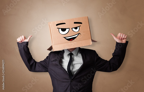 Young man with happy face illustrated cardboard box on his head 