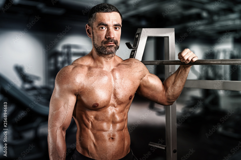 muscular young man lifting weights in epic gym muscular young man lifting weights in epic gym