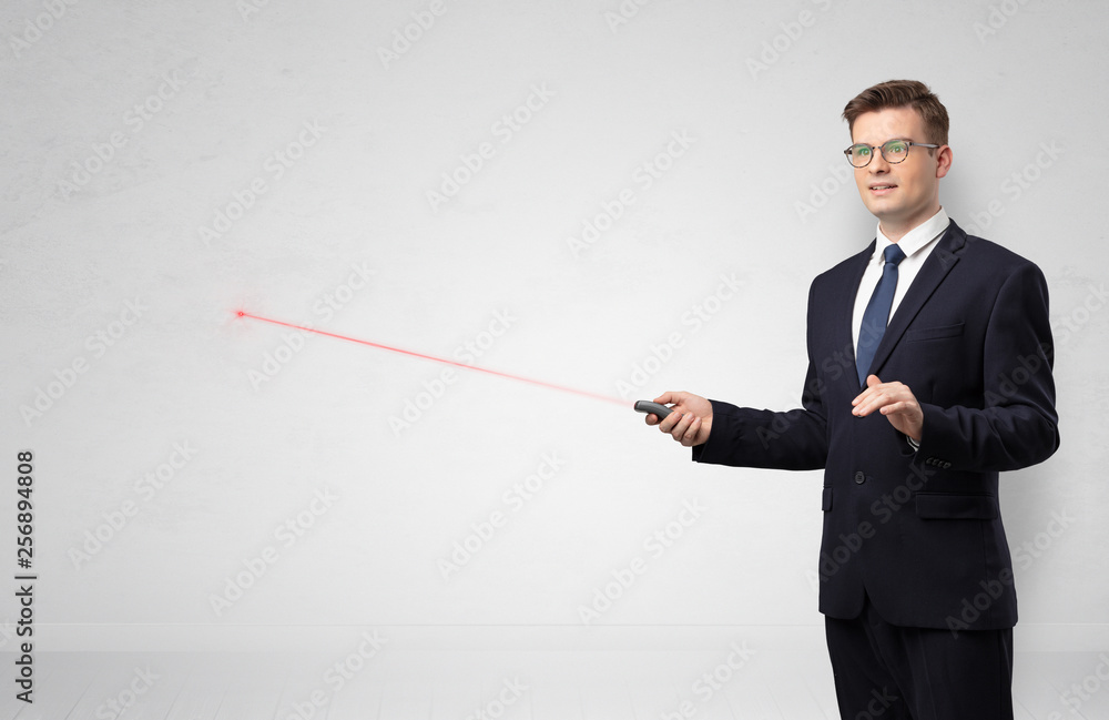 Young businessman with laser pointer and copyspace white wall
