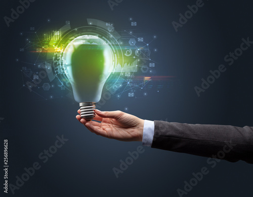 Hand holding light bulb on dark background. New business idea concept