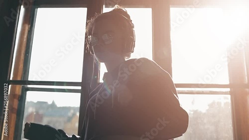 Girl listening to music and dancing near the window
