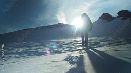 Hiker with backpack climbing top of mountain, mountaineering concept. Man walking snow, hiking in winter. Trekking adventure, people in nature concept. Epic sunset view snow mountain landscape, photo