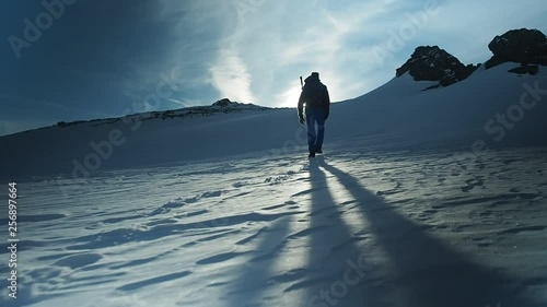 Hiker with backpack climbing top of mountain, mountaineering concept. Man walking snow, hiking in winter. Trekking adventure, people in nature concept. Epic sunset view snow mountain landscape, photo