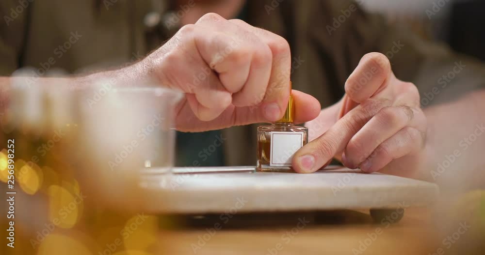 Close up of perfumer screwing small bottle with perfume Close up of perfumer screwing small bottle with perfume