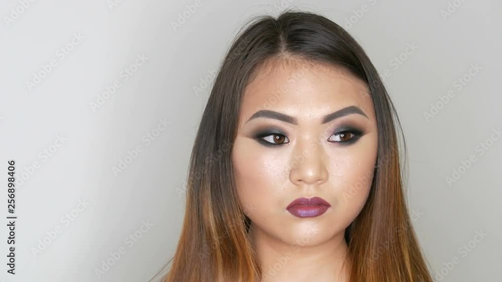 Portrait of a beautiful Asian girl model with bright makeup who poses in a professional studio Portrait of a beautiful Asian girl model with bright makeup who poses in a professional studio