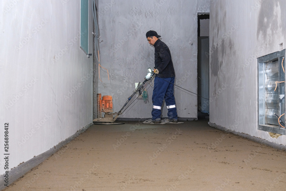 the workers grind the concrete floor at the construction site the workers grind the concrete floor at the construction site