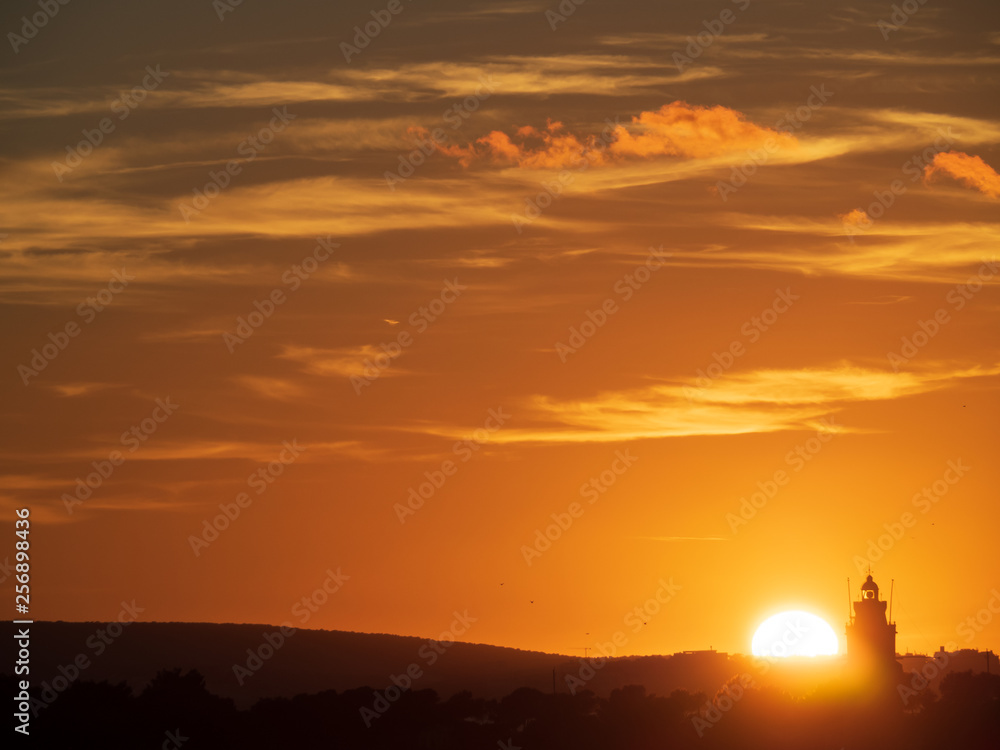 silhouette of lighthouse with red orange sky when sunset