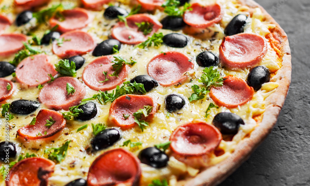 Pizza with Mozzarella cheese, olives, ham, tomato sauce, sausage, pepper, Spices. Italian pizza Italian pizza on wooden table background 