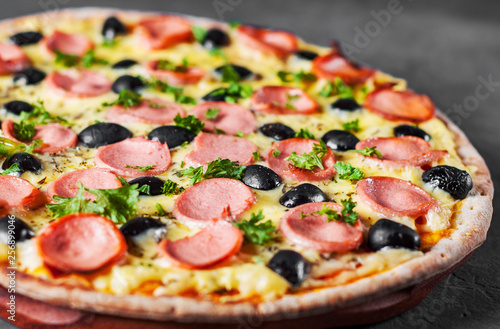 Pizza with Mozzarella cheese, olives, ham, tomato sauce, sausage, pepper, Spices. Italian pizza Italian pizza on wooden table background 