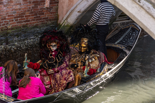 Italy, Venice, carnival 2019, masked people ride in a gondola, a typical and ancient boat.