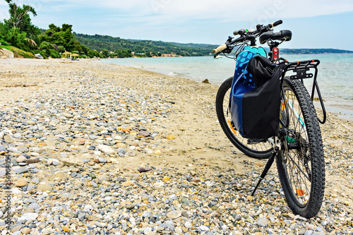      Mountain bike with bag by the sea parked on the beach.