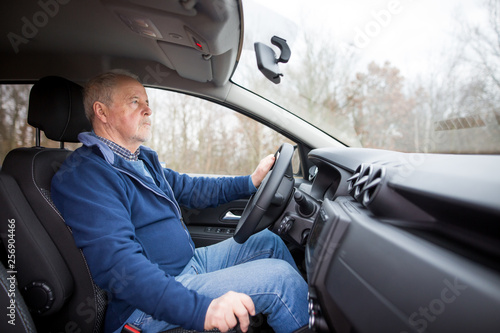 An old senior man driving a modern car, transportation concept