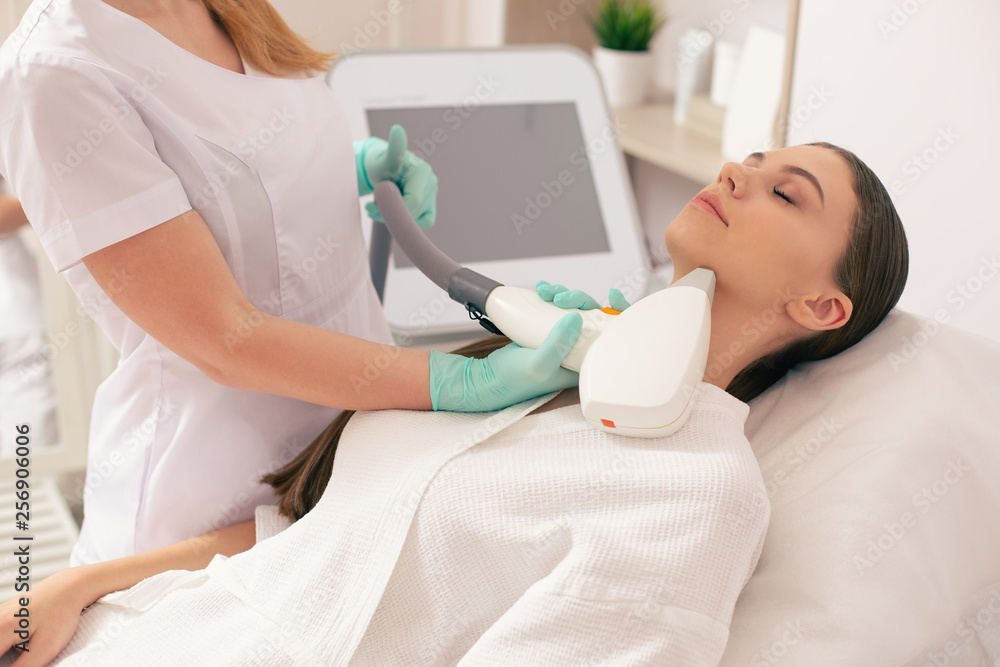 Calm woman enjoying laser hair removal and closing her eyes Calm woman enjoying laser hair removal and closing her eyes