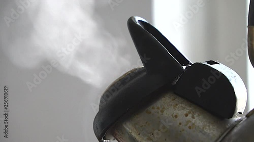 Slow motion boiling old kettle boiling with steam emitted from spout. The camera gently moves to the right. Shallow depth of field. Vintage boiling metal kettle.